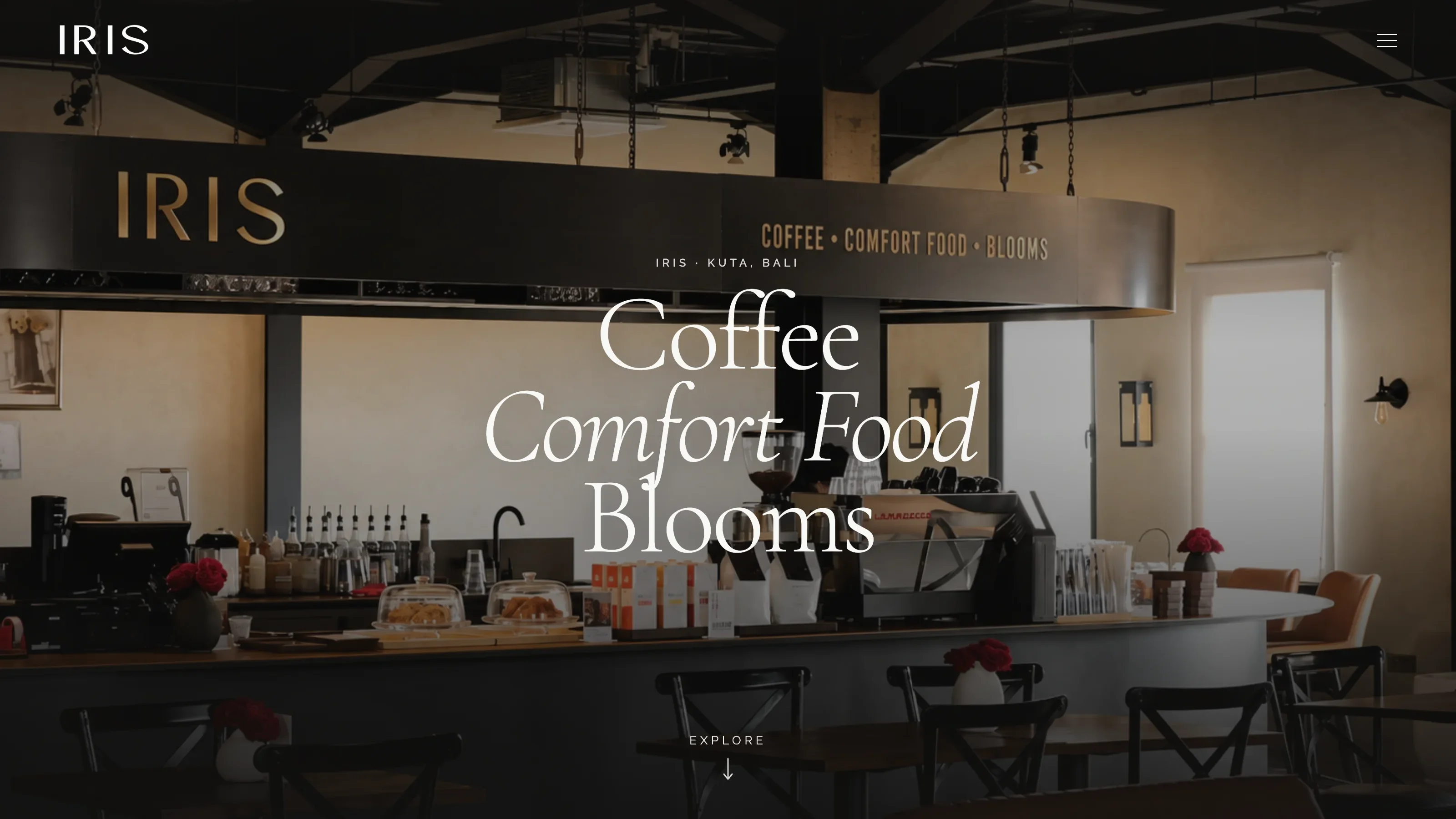 Iris Cafe Bali homepage hero with warm ambient lighting, coffee counter view, and title: Coffee, Comfort Food, Blooms.