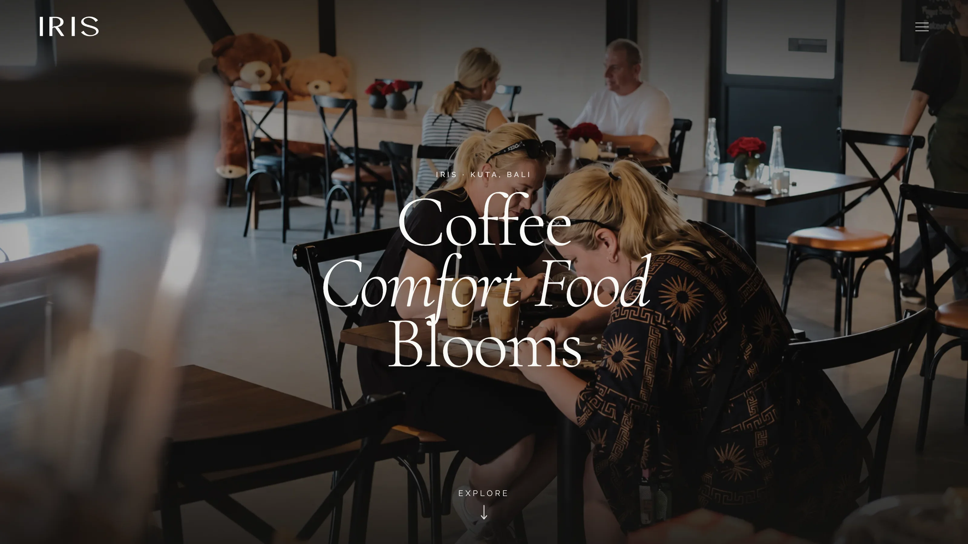 Iris Cafe Bali dining room slide showing guests enjoying coffee and conversation beneath hanging floral arrangements.