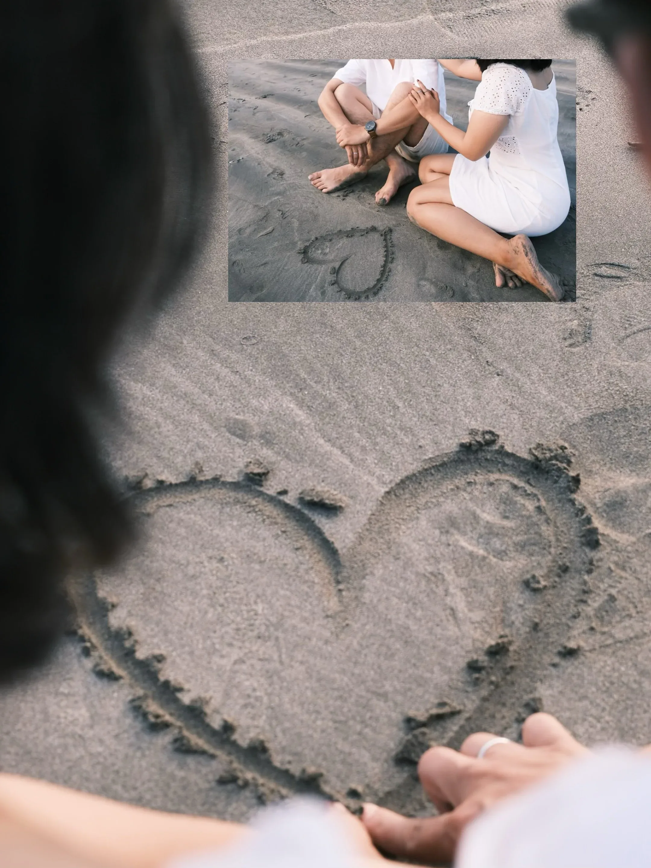 A heart drawn in wet sand, seen over her shoulder, with a smaller frame of the two of them sitting beside it.